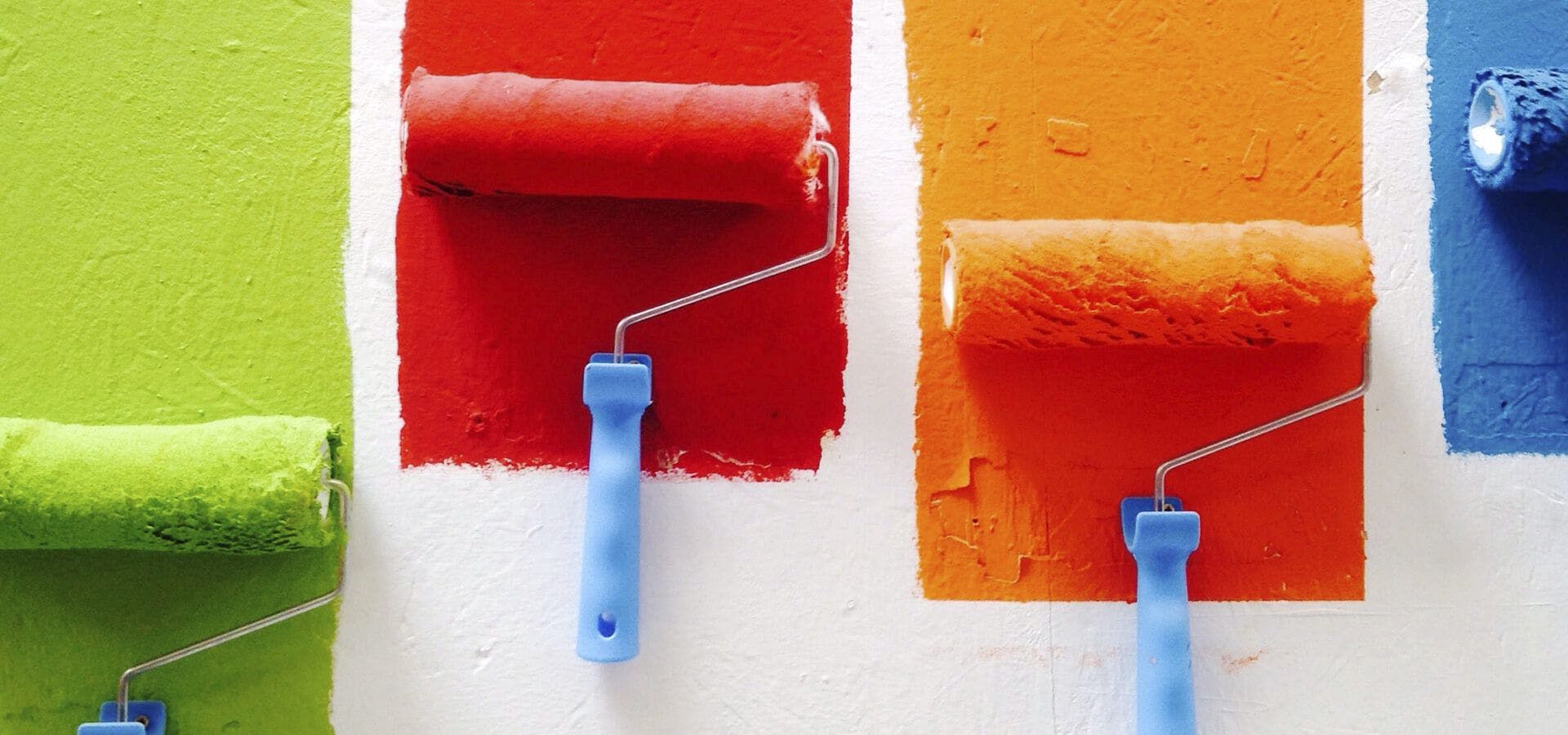 Rodillos pintando pared en distintos colores